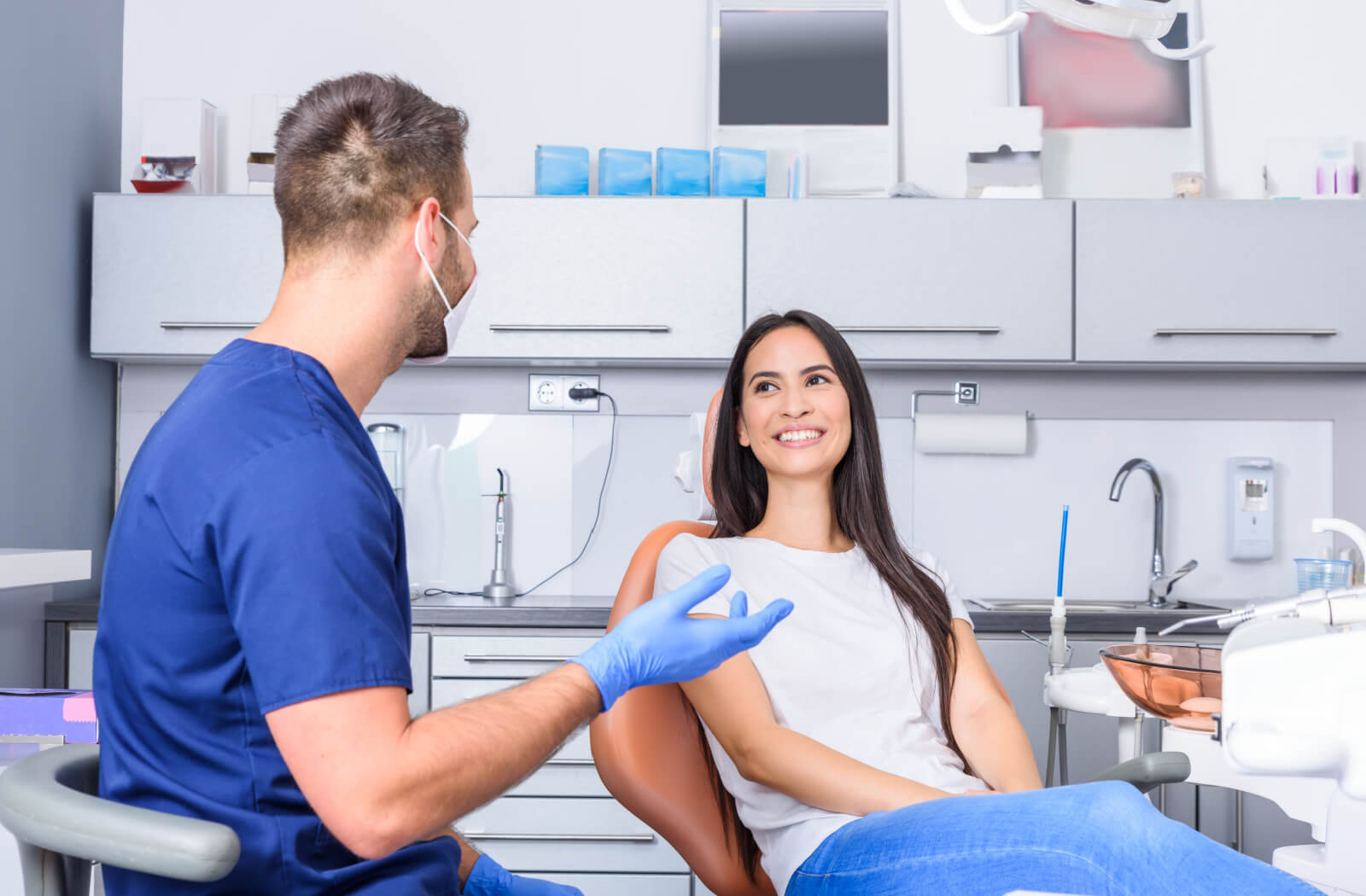 A young woman sitting in a dental office and smiling at her male dentist