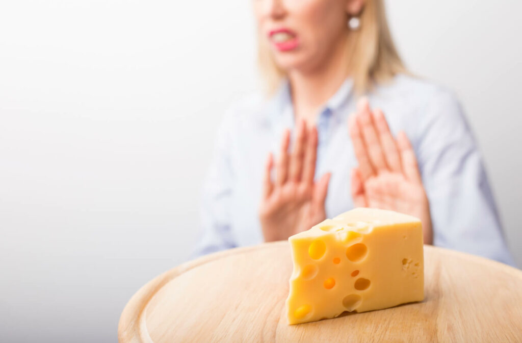 A woman with new dental implants rejects a slice of cheese placed on a cheese board.